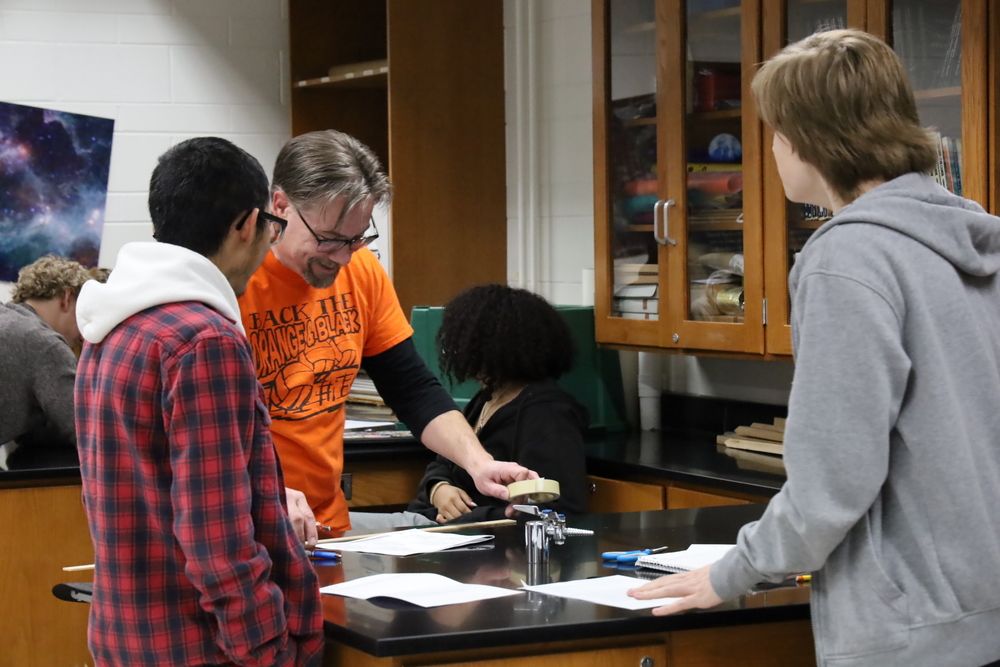 Physics Instructor Eric Jones helps students build devices to catch falling eggs to cushion their fall