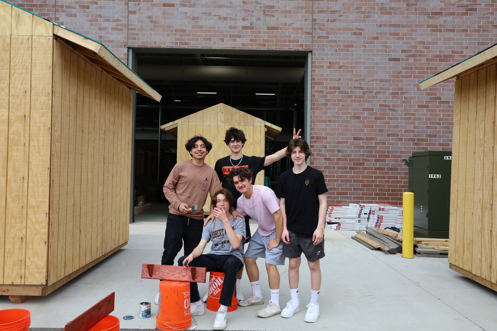 Students posing with shelves they made
