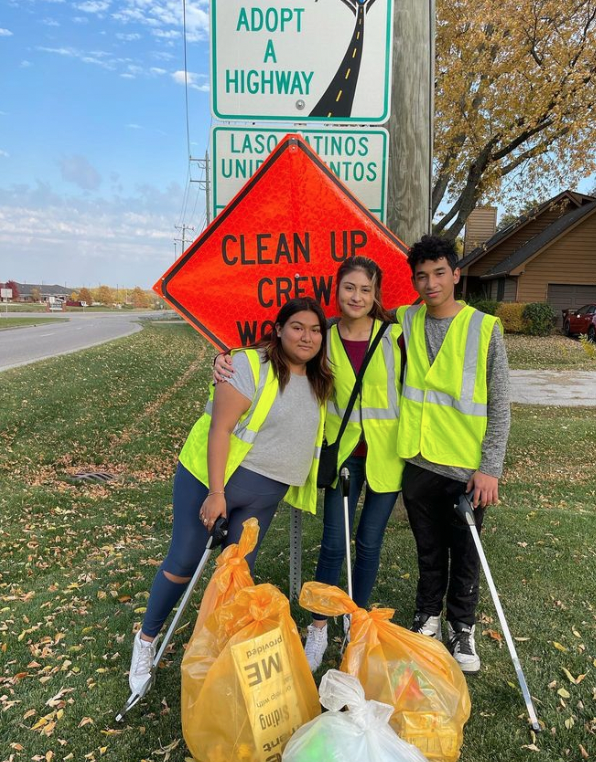 Students in front of the clean up crew sign with their trash bags