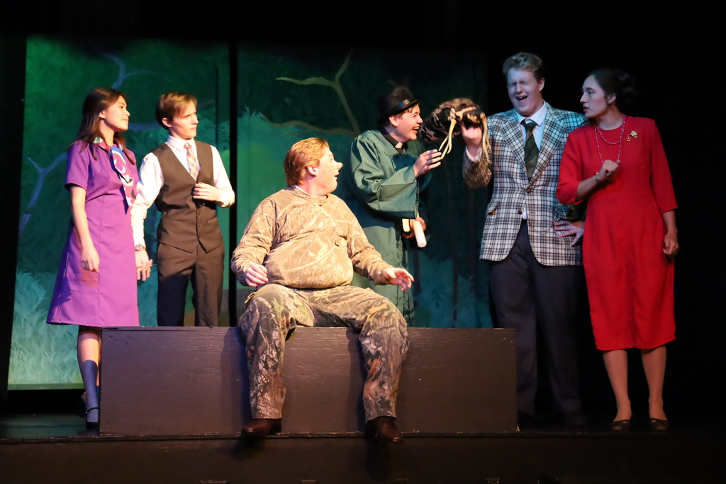 Merry Wives of Windsor cast laughing in the woods. One person in a camo suit