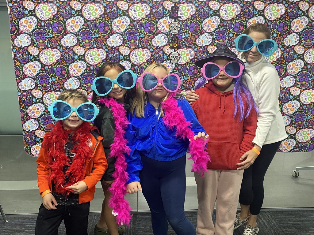 Children and parent posing in sunglasses in front of Day of the Dead backdrop