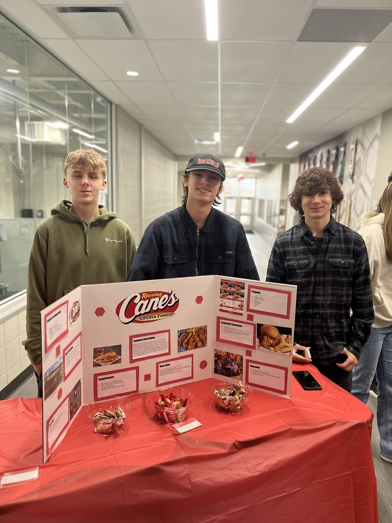 Students with a Raising Cane's poster