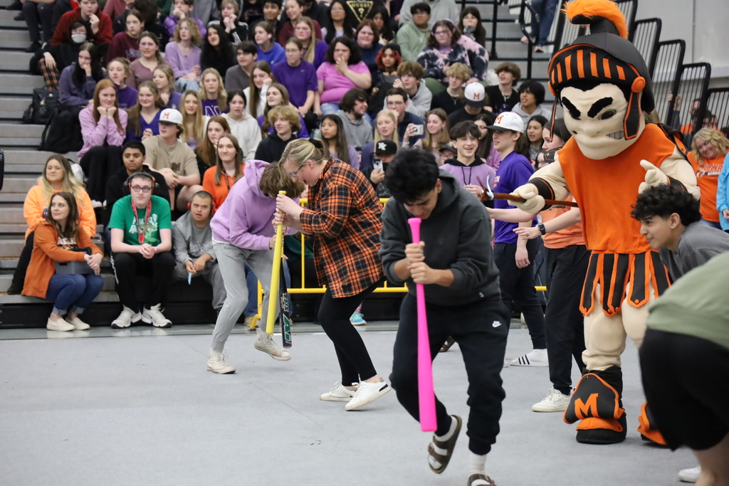A student and staff twirling their head on baseball bats